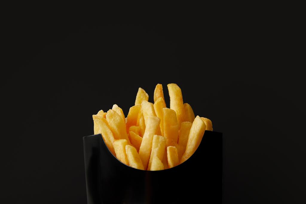 primo piano di scatola nera di deliziose patatine fritte isolate su nero
 - Foto, immagini