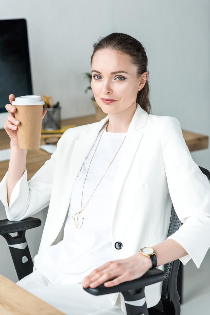 retrato de mulher de negócios sorridente com café para ir sentado no local de trabalho no escritório
 - Foto, Imagem