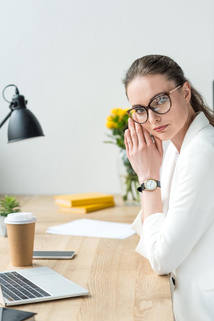 vista laterale di bella donna d'affari in abito bianco e occhiali sul posto di lavoro in ufficio
 - Foto, immagini