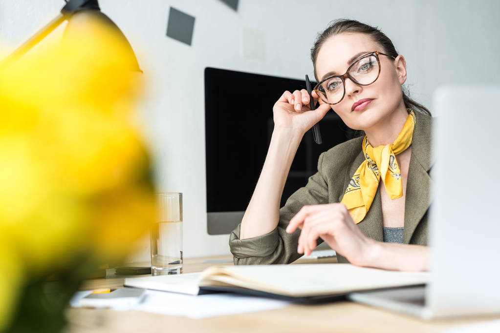 вибірковий фокус красивої стомлюючої стильної бізнес-леді в окулярах, сидячи на робочому місці
 - Фото, зображення