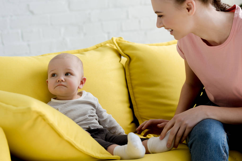 madre sorridente con il bambino seduto sul divano
 - Foto, immagini