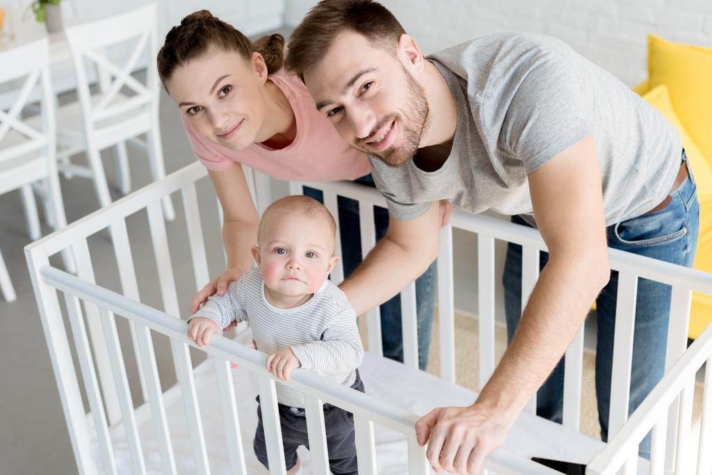 happy parents with little son in baby crib at home - Photo, Image