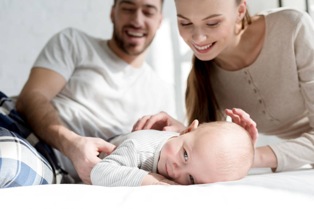 felice madre e padre con il piccolo bambino sul letto
 - Foto, immagini