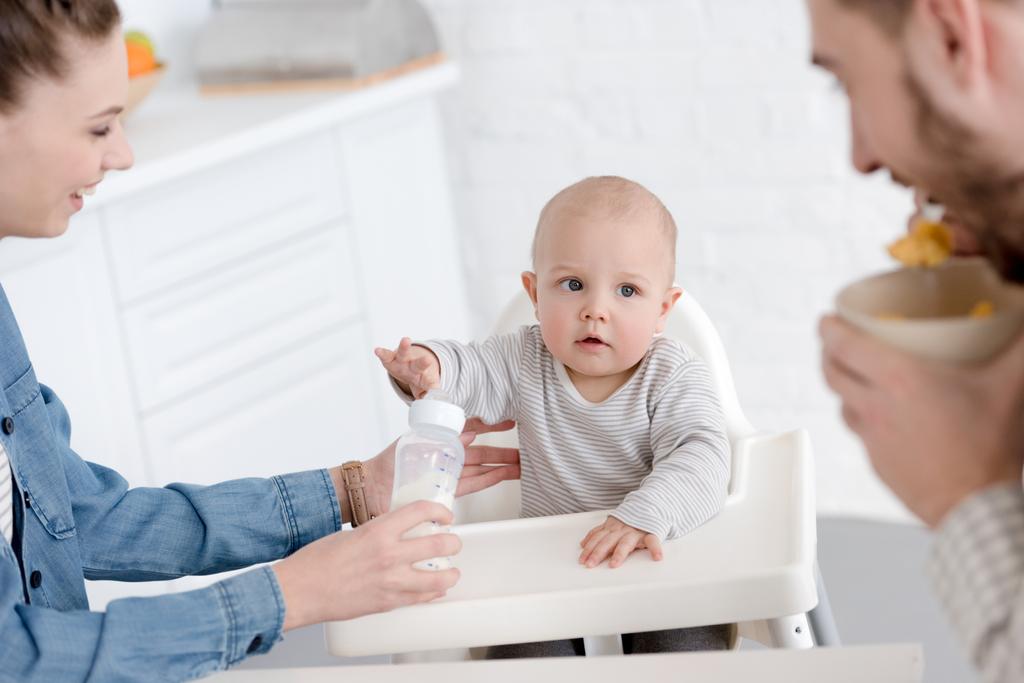 parents nourrissant bébé garçon avec du lait dans le biberon sur la cuisine
 - Photo, image