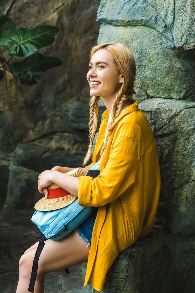 mosolygó fiatal nő Szalmakalapot pihentető a szabadban sziklák - Fotó, kép