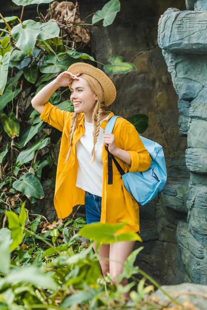 feliz jovem mulher em chapéu de palha com mochila caminhadas na selva
 - Foto, Imagem