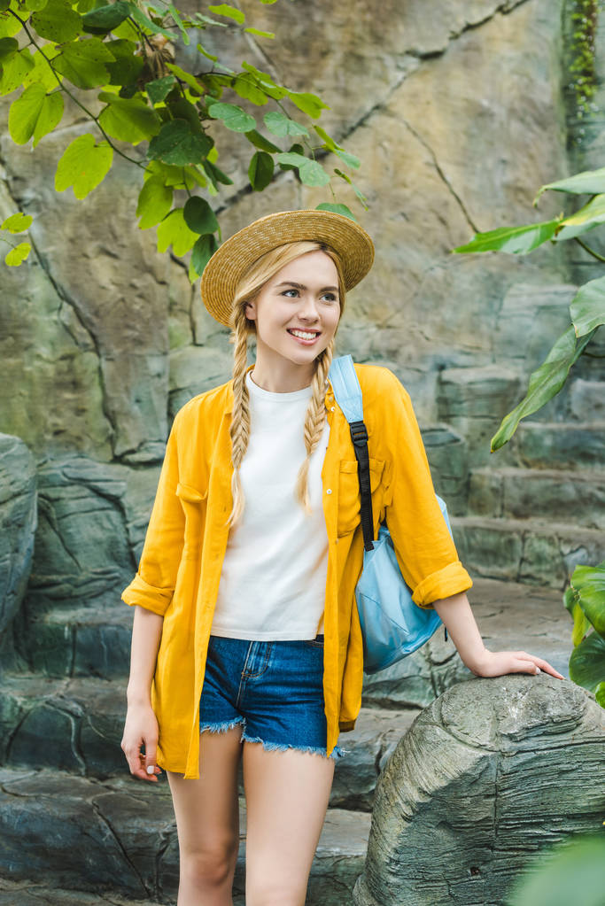 όμορφη νεαρή γυναίκα σε ψάθινο καπέλο στις πέτρινες σκάλες στο πάρκο - Φωτογραφία, εικόνα