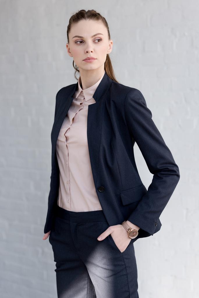mooie vertrouwen zakenvrouw in pak poseren in de buurt van witte muur  - Foto, afbeelding