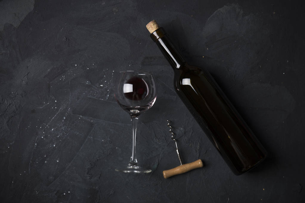 Κόκκινα ποτήρια κρασιού και μπουκάλι σε πέτρινο φόντο. Κάτοψη με χώρο αντιγραφής - Φωτογραφία, εικόνα