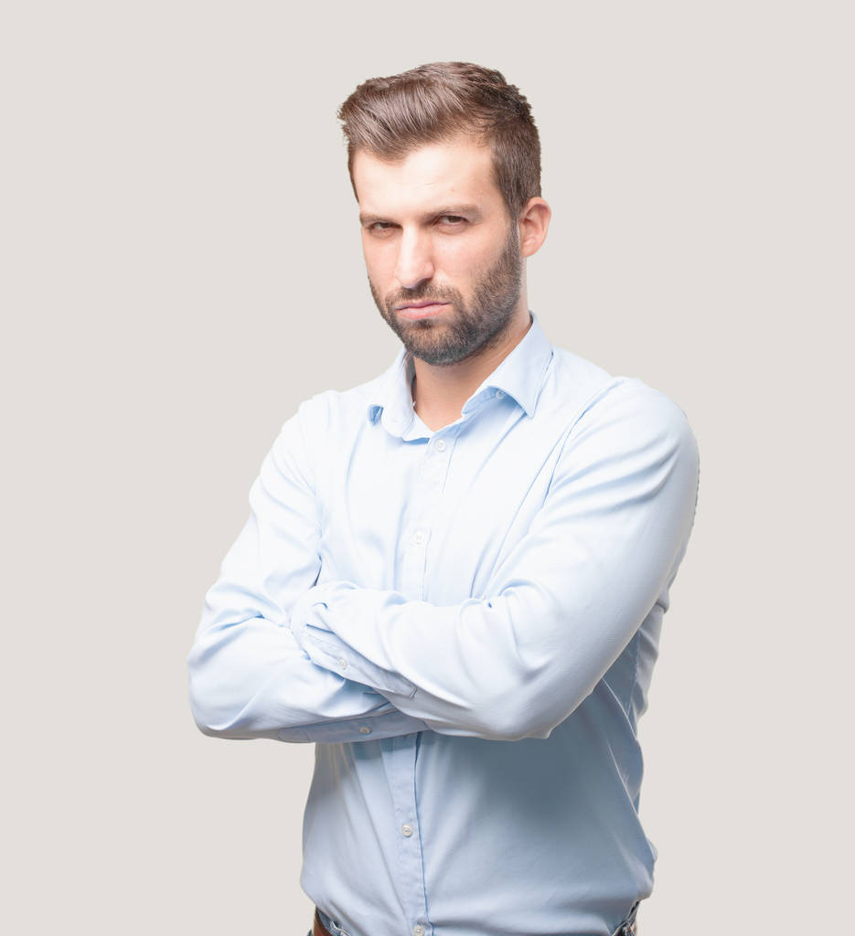 Mladý pohledný muž nesouhlasí a na sobě modré tričko rozzlobený výraz. Člověk izolovaný monochromatické pozadí. - Fotografie, Obrázek