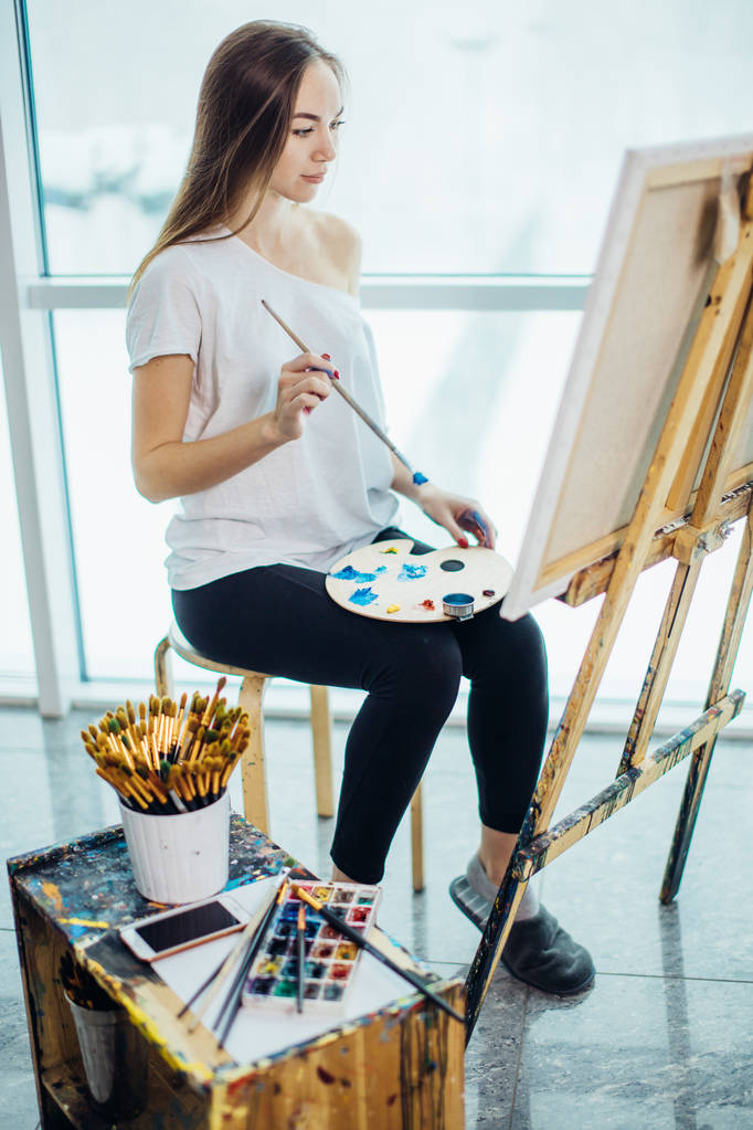 Pintor, chica europea dibujando paisaje marino sobre lienzo en su taller. Concepto de clases de bellas artes
 - Foto, Imagen