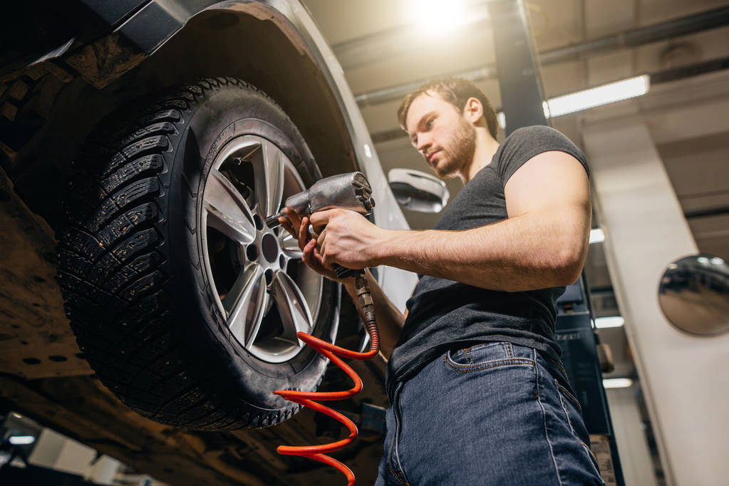 mechanic changing car wheel in auto repair garage - Photo, Image