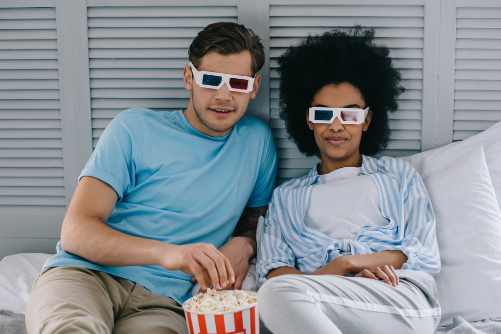 Multiracial couple in 3d glasses watching movie at home with popcorn - Photo, Image