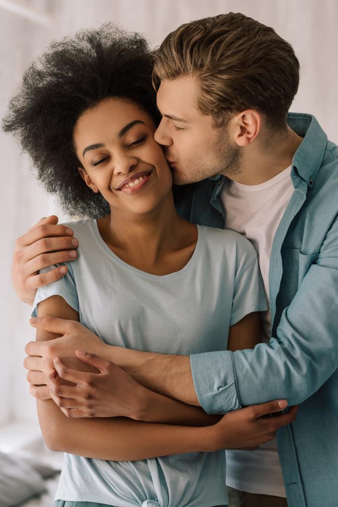 junger Mann umarmt und küsst afrikanische amerikanische Freundin - Foto, Bild