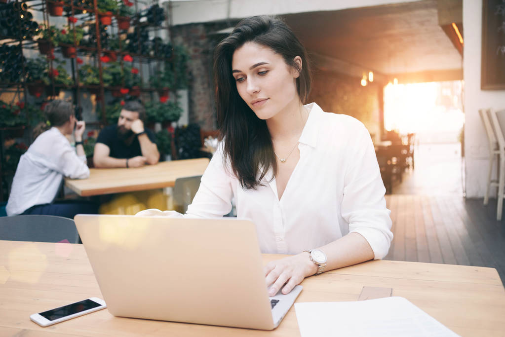 schöne junge Geschäftsfrau arbeitet mit Laptop während der Mittagspause, während sie in einem Café sitzt  - Foto, Bild