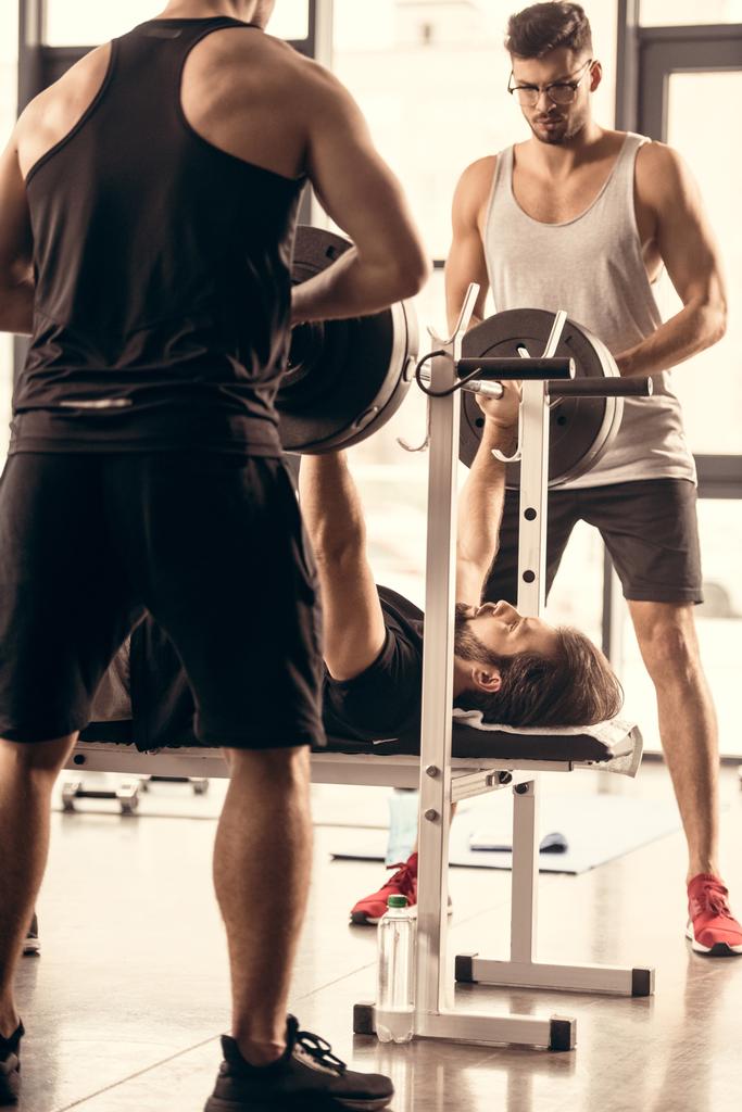 αθλητές βοηθώντας φίλος άσκηση με barbell τύπου πάγκου στο γυμναστήριο - Φωτογραφία, εικόνα