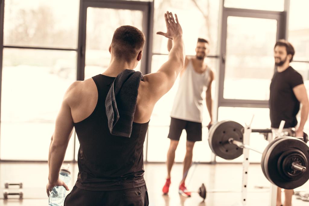 handsome sportsmen waving hands in gym - Photo, Image