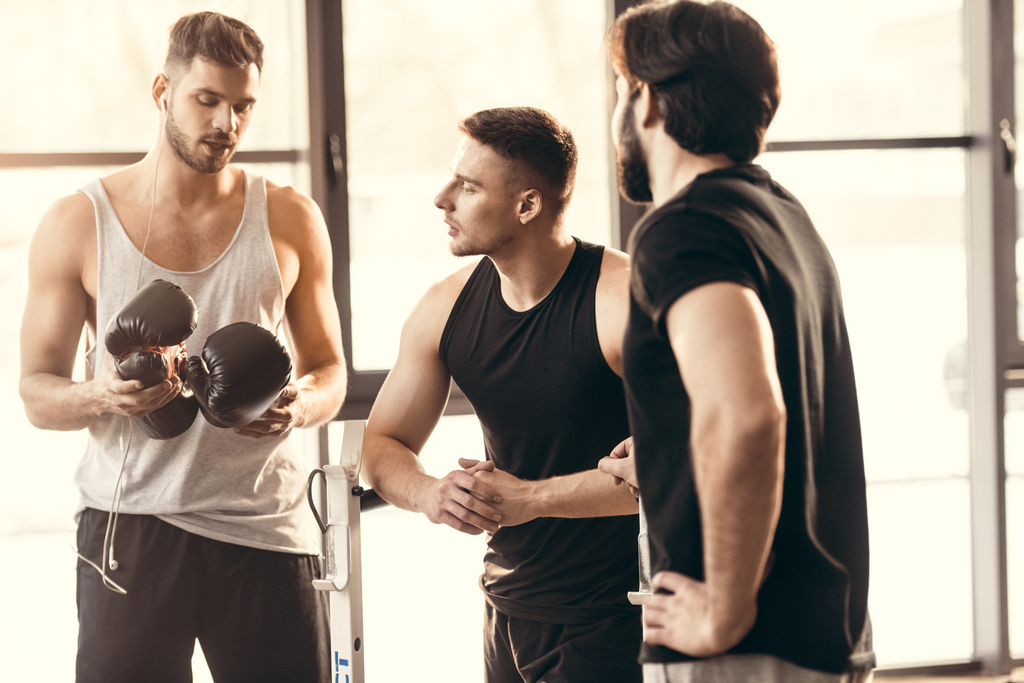 trois jeunes hommes sportifs sur des vêtements de sport parlant dans la salle de gym
  - Photo, image