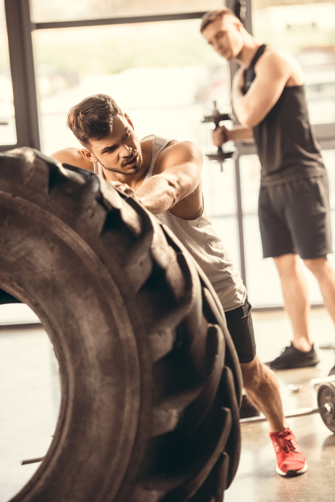 athlète jeune homme en vêtements de sport exercice avec pneu dans la salle de gym
 - Photo, image