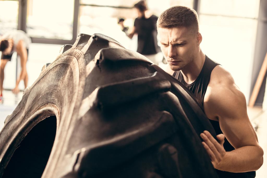 guapo musculoso joven ejercicio con neumático en el gimnasio
 - Foto, Imagen
