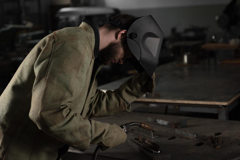 eserleri Fabrikası'nda bakmak için Kaynakçı koruyucu maske kaldırma - Fotoğraf, Görsel