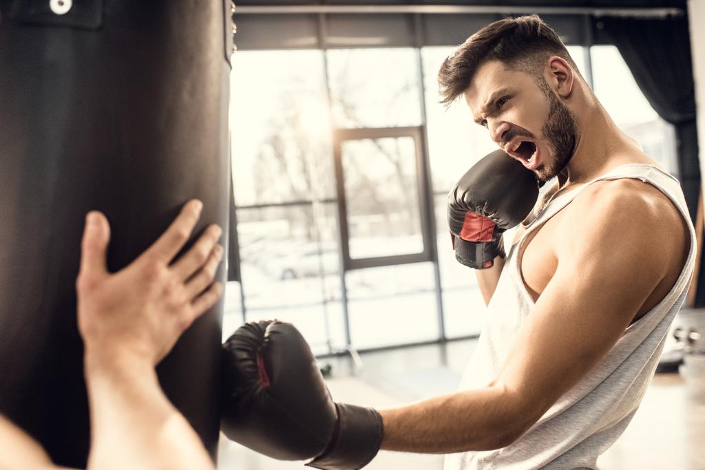 entrenamiento agresivo joven boxeador con saco de boxeo en el gimnasio
 - Foto, imagen