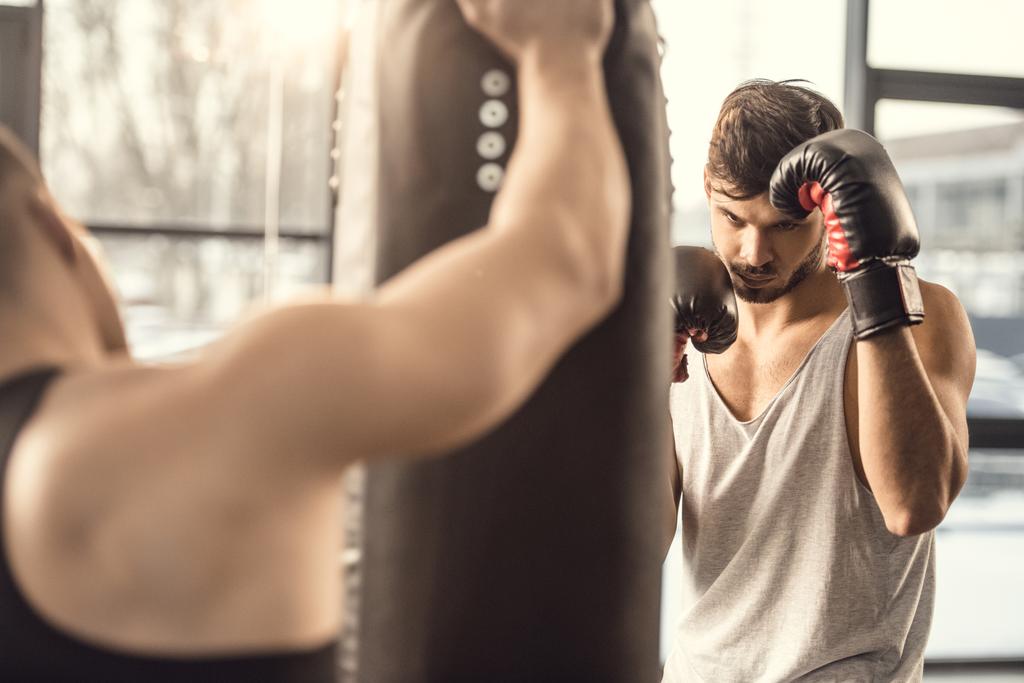 oříznuté shot trenéra drží boxovací pytel zároveň boxer trénink v tělocvičně  - Fotografie, Obrázek
