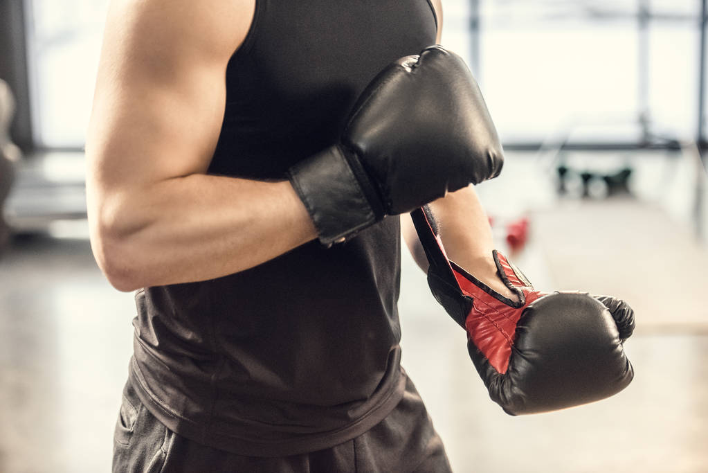 Schnappschuss von muskulösem Sportler mit Boxhandschuhen in Turnhalle - Foto, Bild