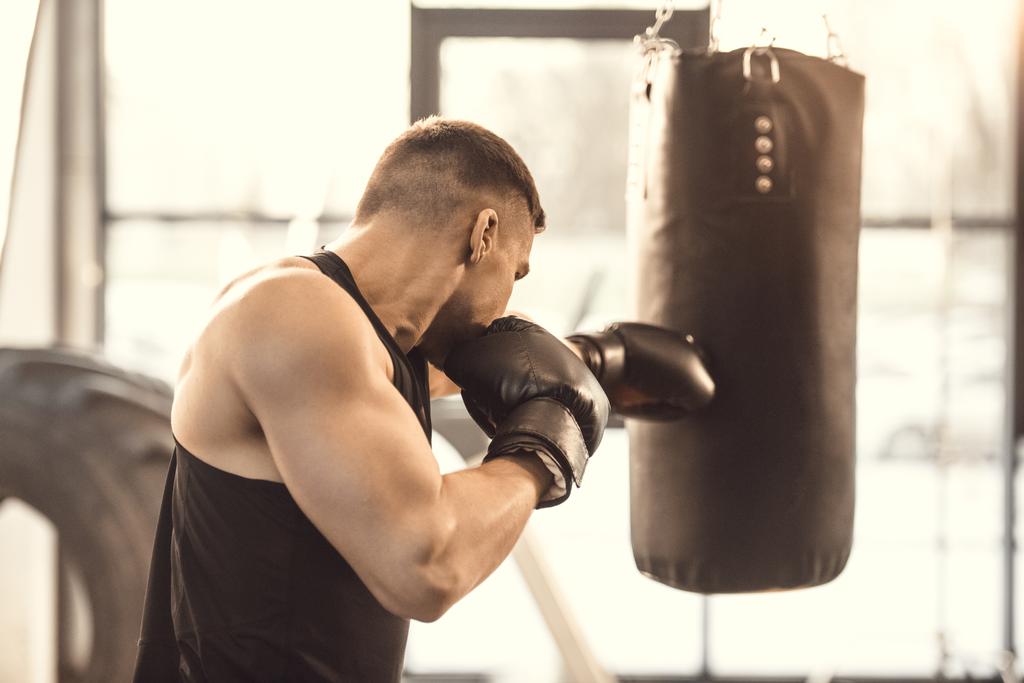 вид збоку м'язистого молодого боксера тренувань з мішком для ударів
 - Фото, зображення