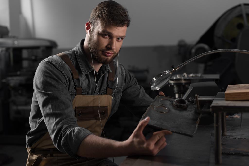 retrato de un joven trabajador masculino en auriculares con parte metálica bajo lupa
 - Foto, imagen