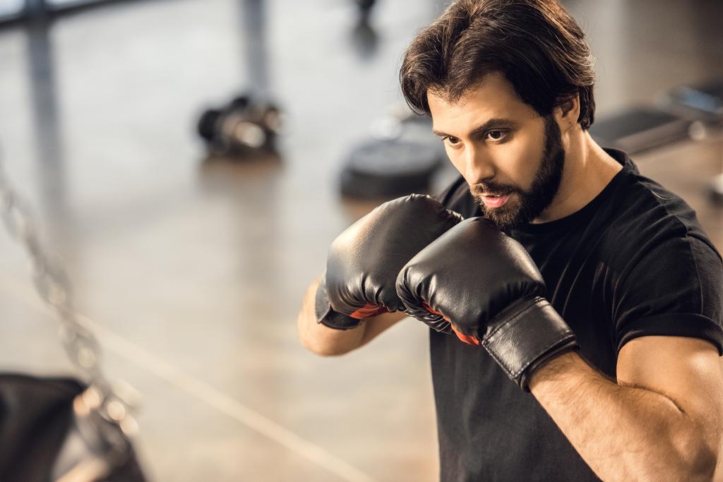 handsome focused young man in boxing gloves exercising in sports center - Photo, Image