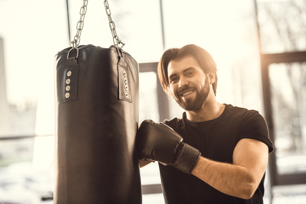 красивый молодой человек боксирует и улыбается перед камерой в спортзале
 - Фото, изображение