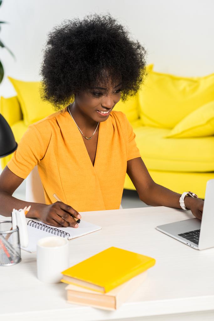 усміхнений афроамериканський фрілансер, що працює на ноутбуці на робочому місці вдома
 - Фото, зображення