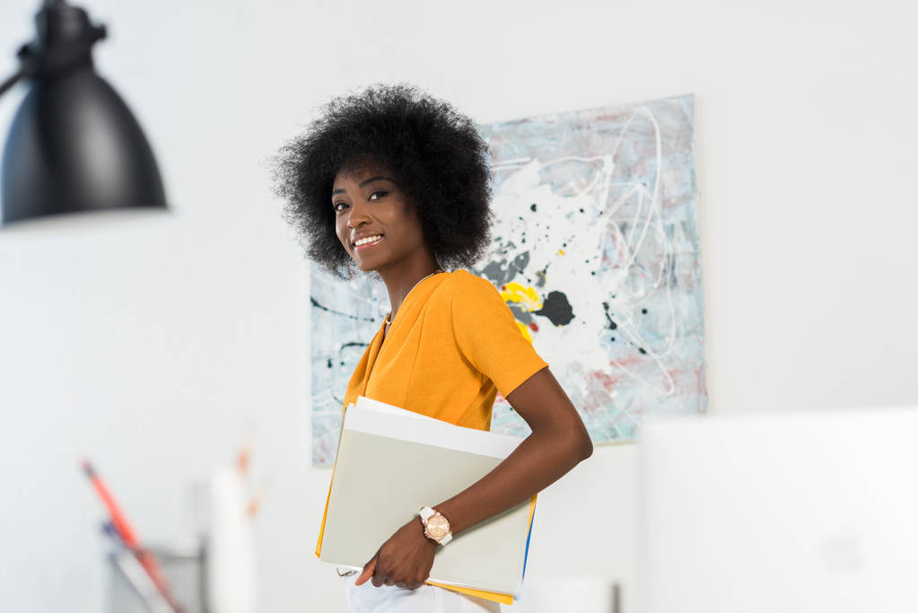 widok boczny uśmiechający się african american freelancer z artykuły w ręce w home office - Zdjęcie, obraz
