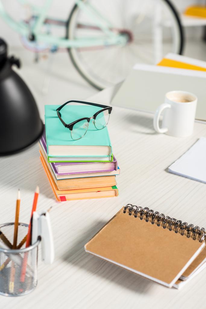 Zamknij widok stosy książek, notebooki, foldery, filiżankę kawy i okulary w miejscu pracy w domu office - Zdjęcie, obraz