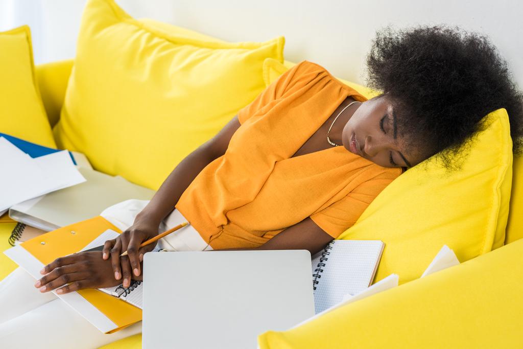 κουρασμένος αφρικανική αμερικανική freelancer στον ύπνο στον καναπέ με το laptop και έγγραφα στο σπίτι - Φωτογραφία, εικόνα