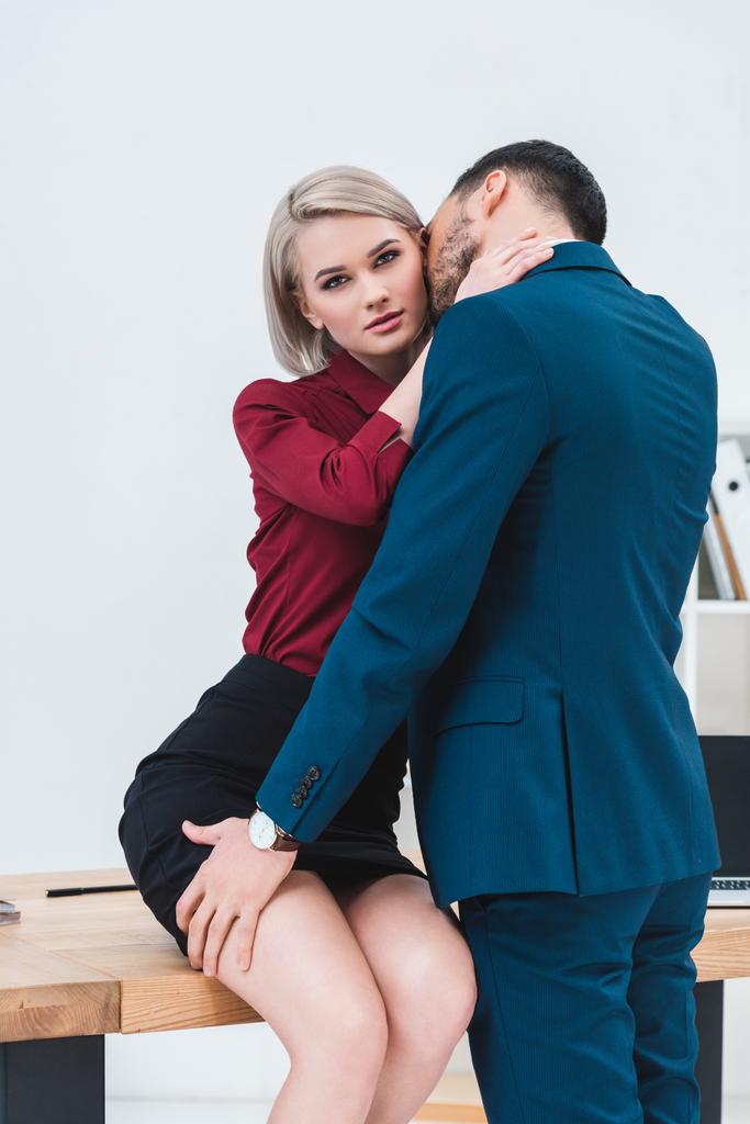 sexy joven pareja de personas de negocios besándose y coqueteando en el lugar de trabajo
 - Foto, Imagen