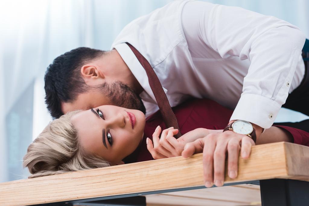 businessman kissing beautiful young businesswoman on table in office - Photo, Image