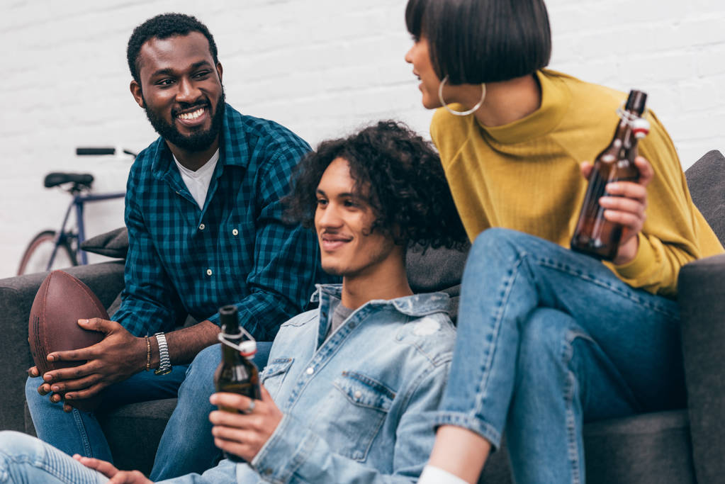 jóvenes amigos multiculturales con botellas de cerveza y pelota para el fútbol americano
  - Foto, imagen