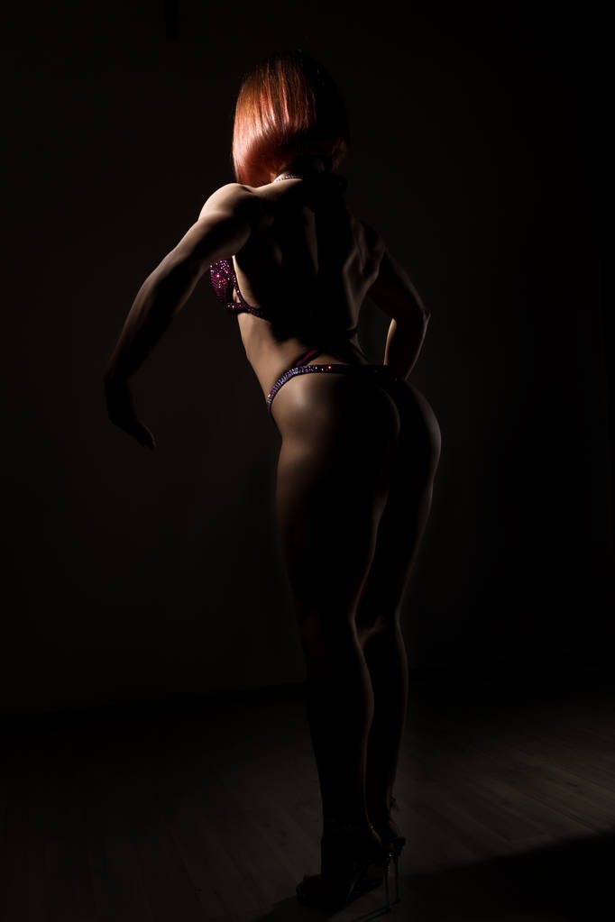 красива фітнес-леді, м'язова дівчина позує на темному тлі. жіноче бодібілдинг
 - Фото, зображення