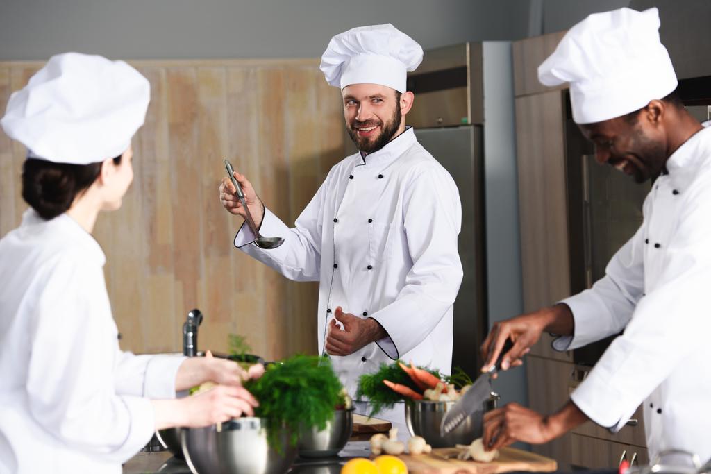 Equipe de chefs multirraciais cozinhar juntos por balcão de cozinha
 - Foto, Imagem