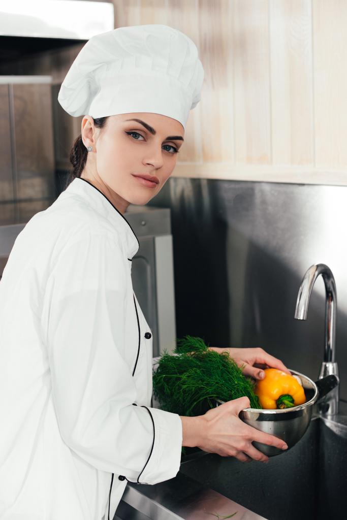 Młoda kobieta kucharz mycie warzyw w kuchni - Zdjęcie, obraz