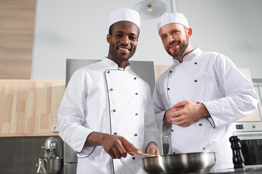 Многорасовая команда поваров-мужчин, работающих вместе на печи
 - Фото, изображение