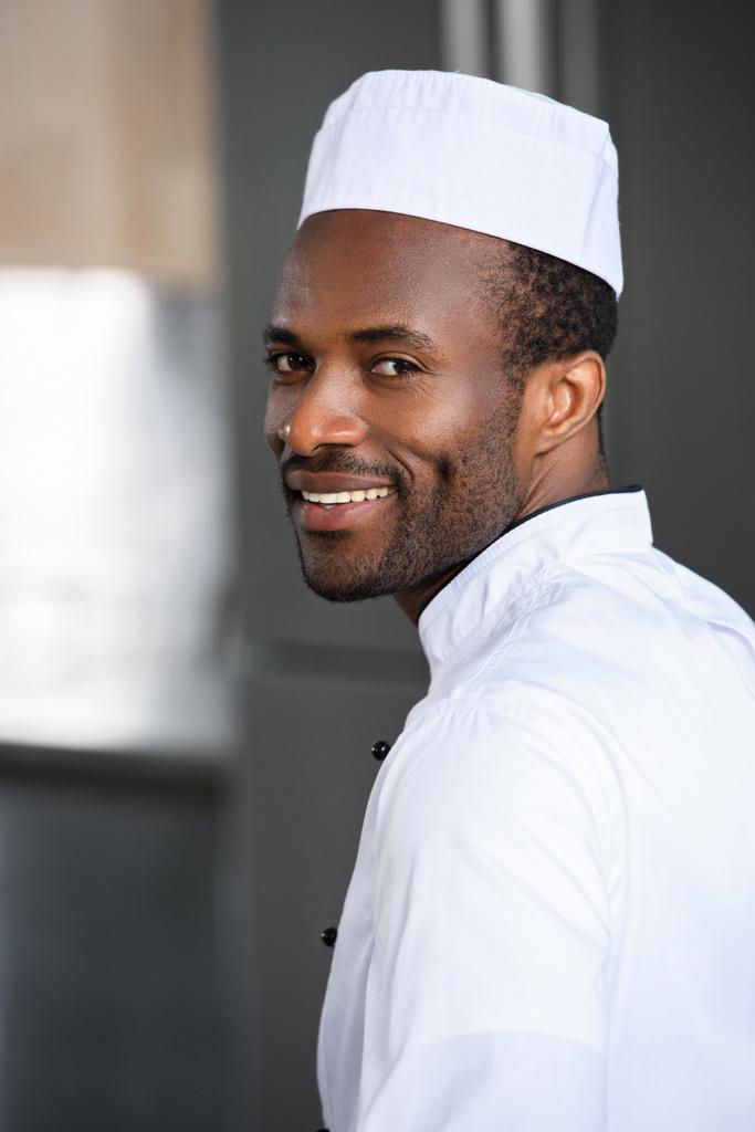 muotokuva hymyilevä komea afrikkalainen amerikkalainen kokki katselee kameraa ravintolan keittiössä
 - Valokuva, kuva