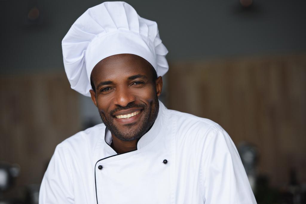 ritratto di un bel cuoco afro-americano che guarda la macchina fotografica alla cucina del ristorante
 - Foto, immagini