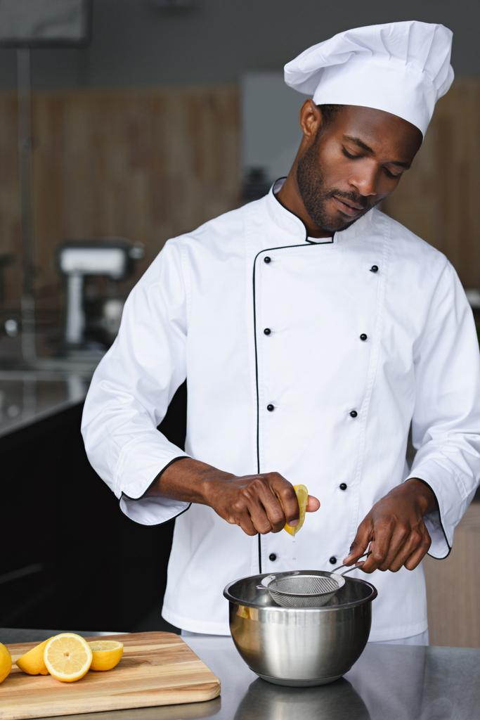 guapo afroamericano chef exprimir limones en restaurante cocina
 - Foto, imagen