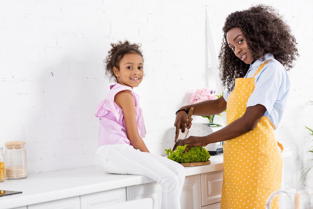 Африканский американец и дочь режут салат на кухне
 - Фото, изображение