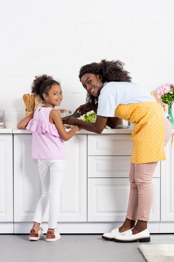 african american mother and daughter cutting vegetables on kitchen - Photo, Image