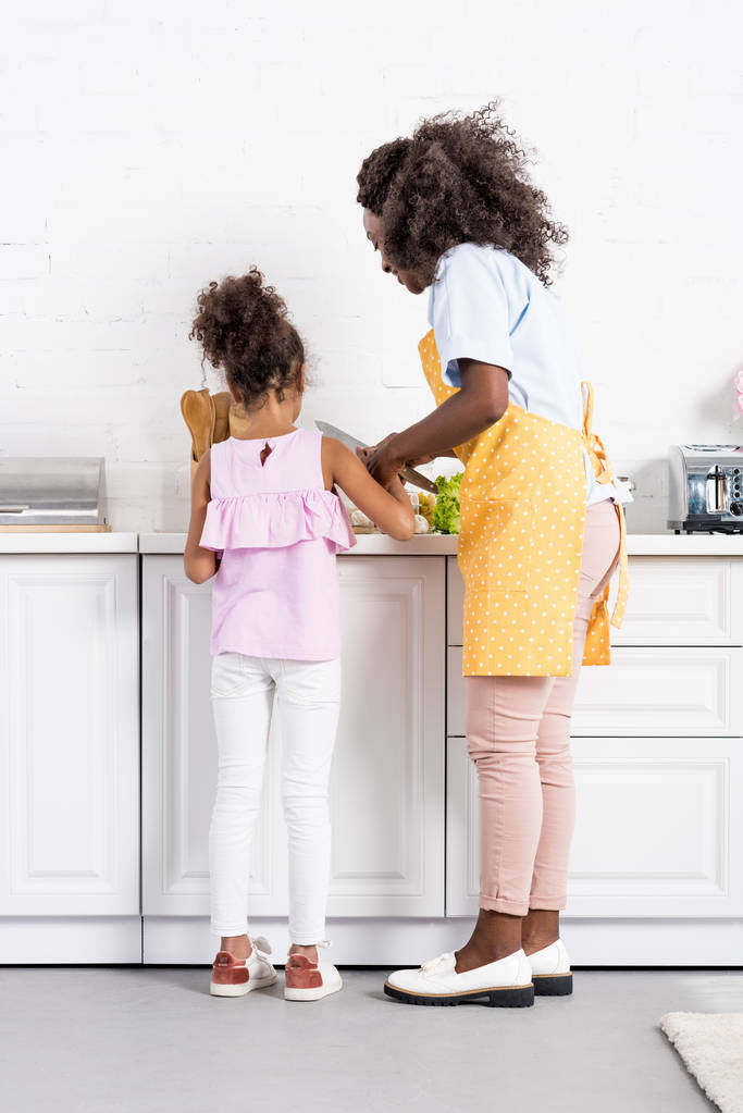 アフリカ系アメリカ人の母と娘カット野菜一緒にキッチンに - 写真・画像