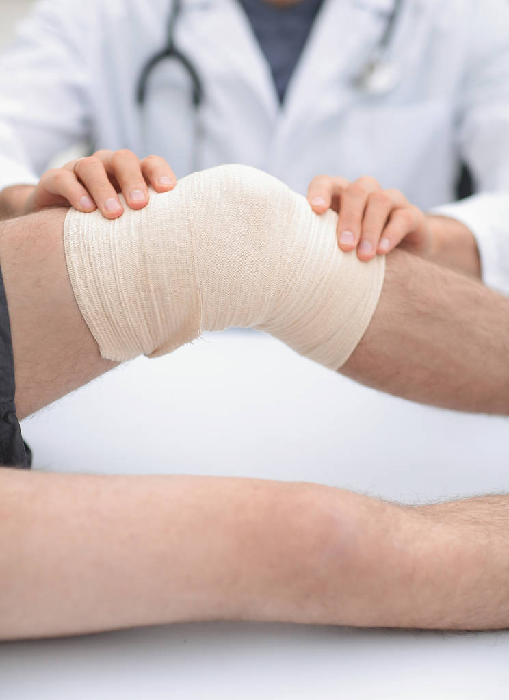 Traumatologe, der einen Verband am Knie anlegt - Foto, Bild